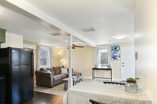 living room featuring a ceiling fan, visible vents, dark wood-style flooring, and baseboards