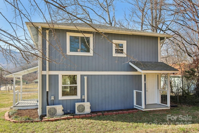 rear view of house with a yard, roof with shingles, and ac unit