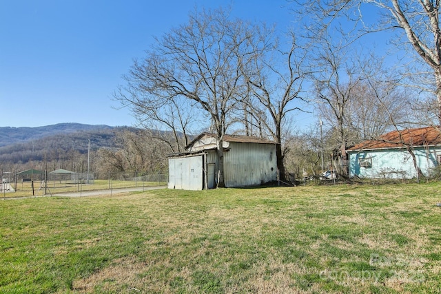 view of yard with an outbuilding, a mountain view, and fence