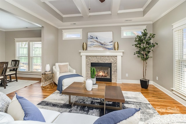 living area featuring crown molding, plenty of natural light, a tiled fireplace, and wood finished floors