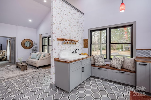 kitchen with pendant lighting, sink, gray cabinets, high vaulted ceiling, and tile patterned floors