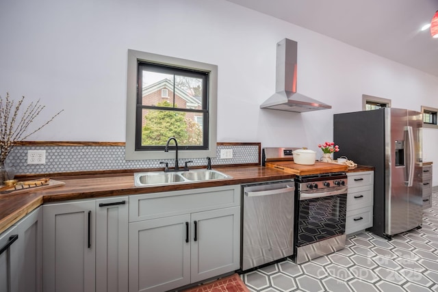 kitchen with island range hood, sink, butcher block counters, gray cabinetry, and stainless steel appliances