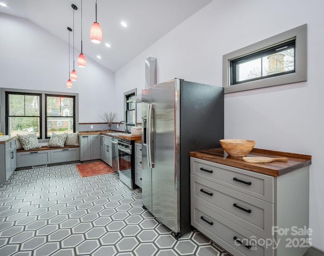 kitchen featuring decorative light fixtures, stainless steel appliances, wooden counters, and a healthy amount of sunlight