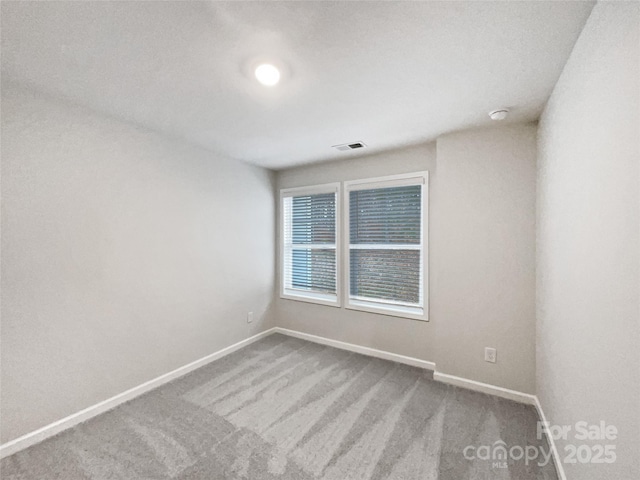 carpeted spare room featuring visible vents and baseboards