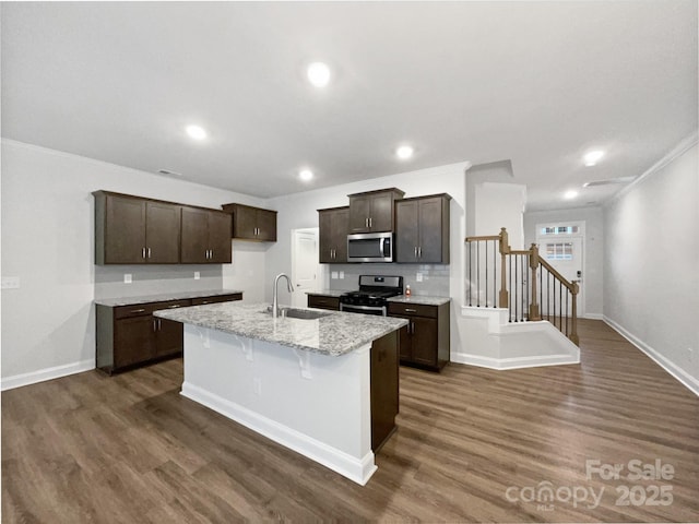 kitchen featuring dark wood finished floors, a center island with sink, stainless steel appliances, and a sink