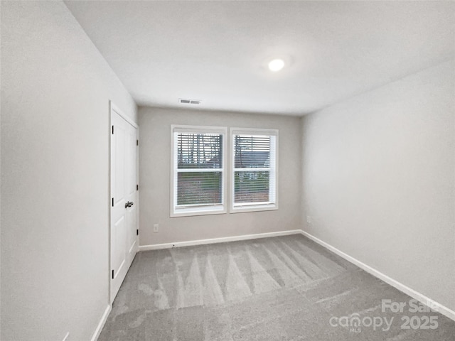 unfurnished room with baseboards, visible vents, and light colored carpet