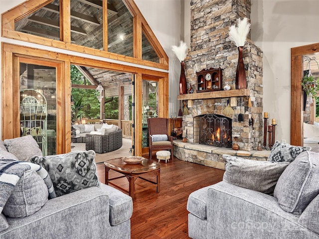 living room with hardwood / wood-style flooring, a stone fireplace, and high vaulted ceiling