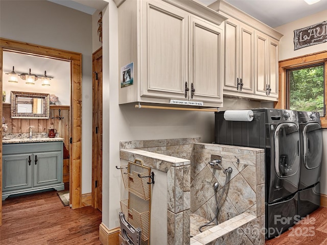 laundry room with cabinets, washing machine and dryer, dark wood-type flooring, and sink