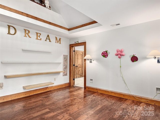 spare room featuring lofted ceiling and dark hardwood / wood-style floors