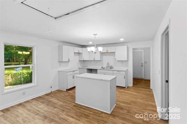 kitchen featuring sink, white cabinetry, a center island, light hardwood / wood-style flooring, and pendant lighting