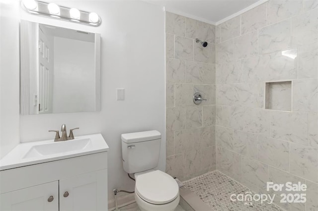 bathroom with ornamental molding, vanity, toilet, and a tile shower