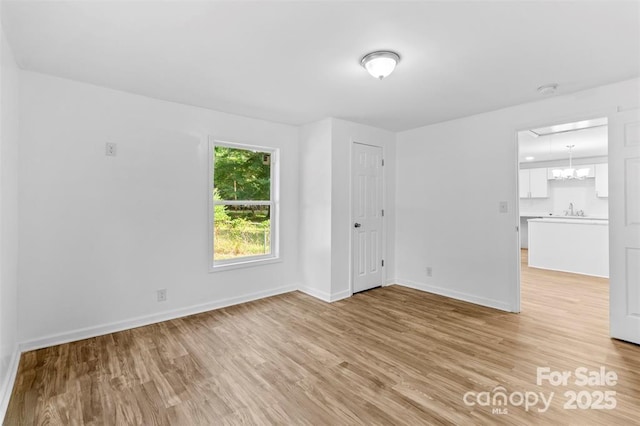 spare room featuring a notable chandelier, light hardwood / wood-style flooring, and sink