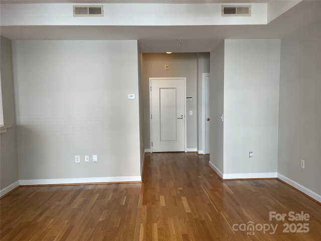 corridor featuring wood finished floors, visible vents, and baseboards