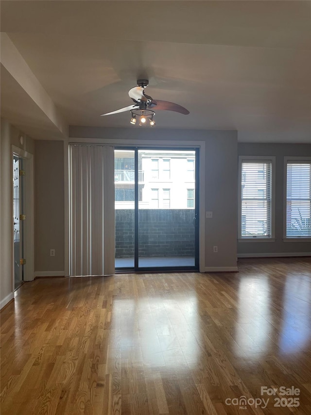 unfurnished room featuring a ceiling fan, baseboards, and wood finished floors