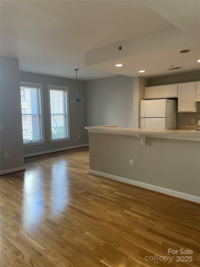 unfurnished living room with recessed lighting, baseboards, and light wood finished floors