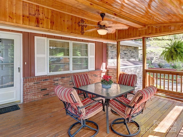 sunroom with a ceiling fan, outdoor dining area, and beamed ceiling