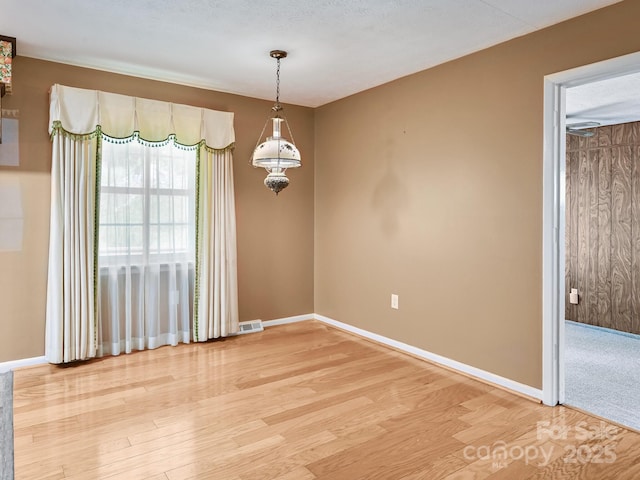 empty room featuring baseboards, light wood-type flooring, and visible vents