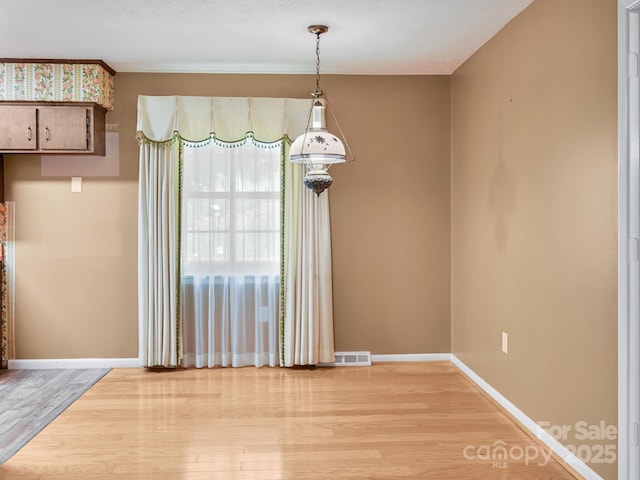 unfurnished dining area with baseboards, visible vents, and light wood finished floors