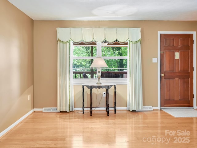 entrance foyer featuring baseboards, visible vents, and wood finished floors