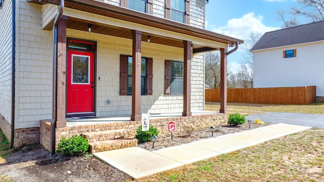 property entrance with covered porch and fence