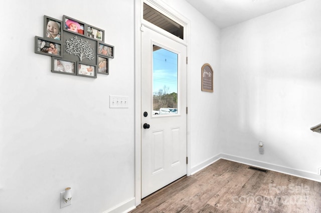 doorway featuring baseboards, visible vents, and wood finished floors