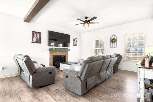 living room featuring a brick fireplace, plenty of natural light, ceiling fan, and wood finished floors