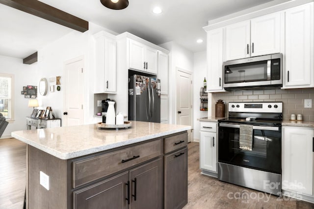 kitchen featuring decorative backsplash, appliances with stainless steel finishes, wood finished floors, beamed ceiling, and white cabinetry