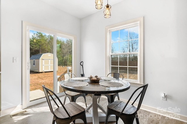 dining area featuring light wood-type flooring, visible vents, and baseboards