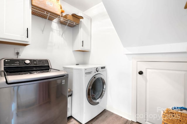 laundry area with cabinet space, light wood-style flooring, and separate washer and dryer