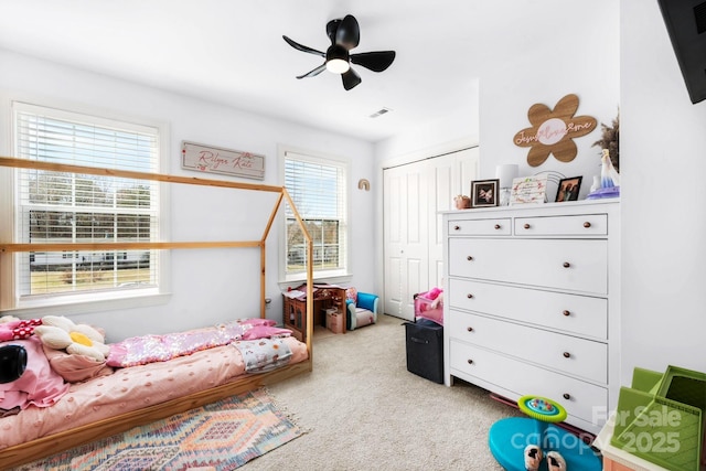 bedroom with a closet, carpet flooring, visible vents, and a ceiling fan