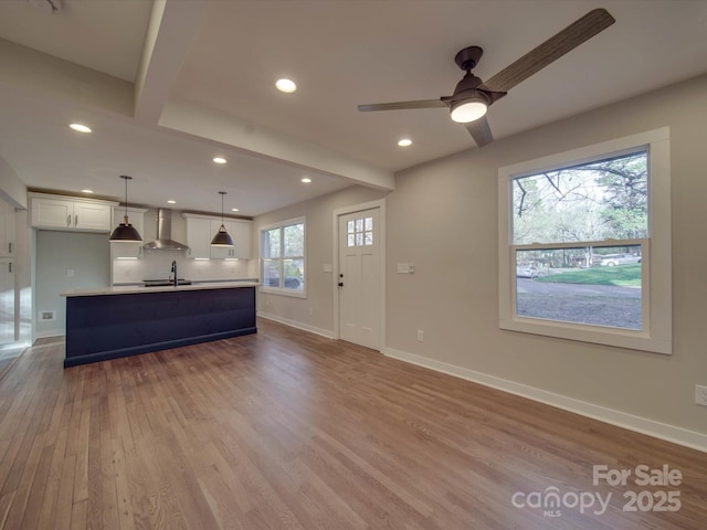 unfurnished living room with ceiling fan, sink, and light hardwood / wood-style flooring