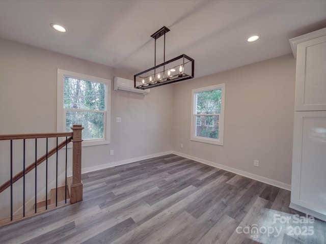 unfurnished dining area with hardwood / wood-style flooring and a wall mounted AC