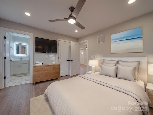 bedroom with hardwood / wood-style flooring, ceiling fan, and ensuite bath