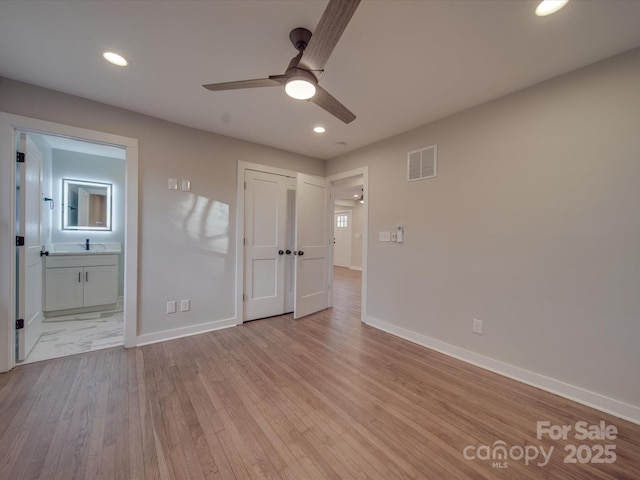 unfurnished bedroom featuring ceiling fan, sink, light hardwood / wood-style floors, and ensuite bath