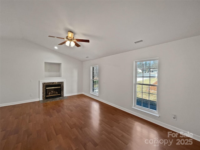 unfurnished living room with visible vents, baseboards, vaulted ceiling, a high end fireplace, and dark wood-style floors