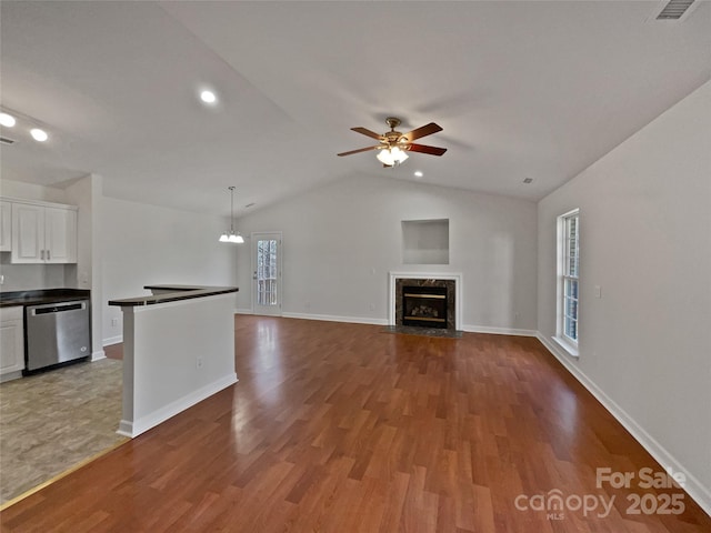 unfurnished living room with vaulted ceiling, ceiling fan with notable chandelier, a fireplace, and light hardwood / wood-style floors