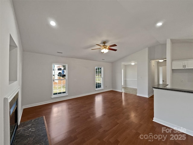 unfurnished living room featuring ceiling fan, dark hardwood / wood-style floors, vaulted ceiling, and a fireplace