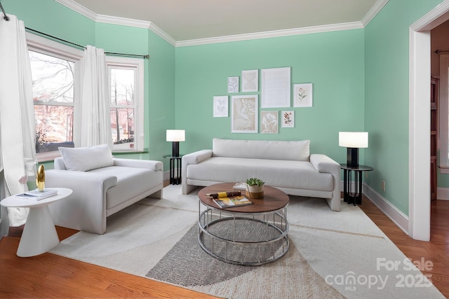 living area featuring crown molding, baseboards, and wood finished floors