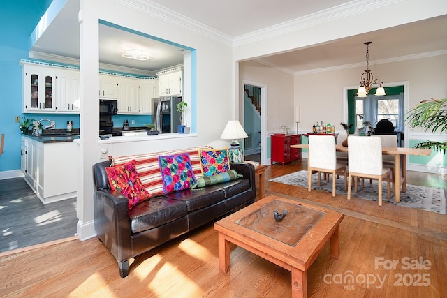 living room featuring ornamental molding, light wood-style flooring, and baseboards