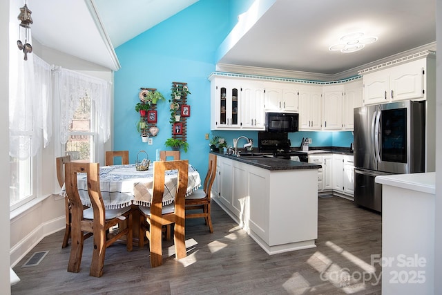 kitchen featuring dark countertops, a peninsula, black appliances, white cabinetry, and a sink