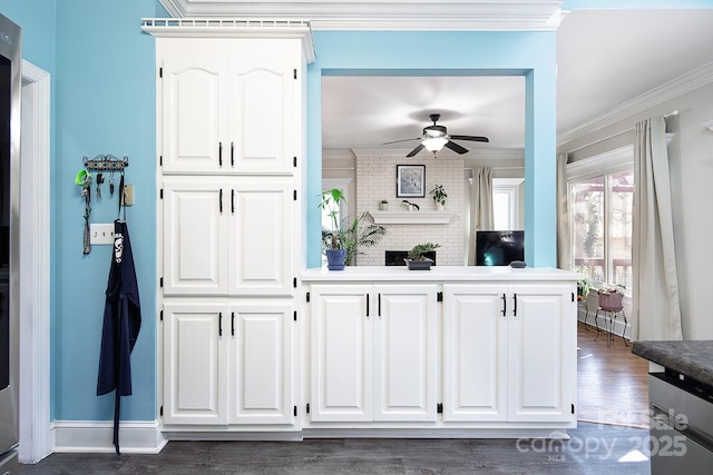 interior space featuring dark wood-type flooring, white cabinetry, crown molding, and a ceiling fan