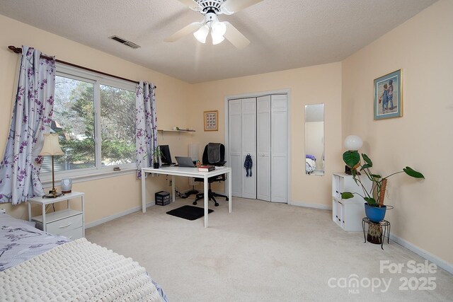 carpeted bedroom with a textured ceiling, a closet, visible vents, and baseboards