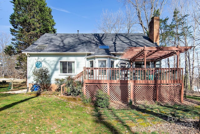 back of house featuring a wooden deck, a chimney, a pergola, and a yard