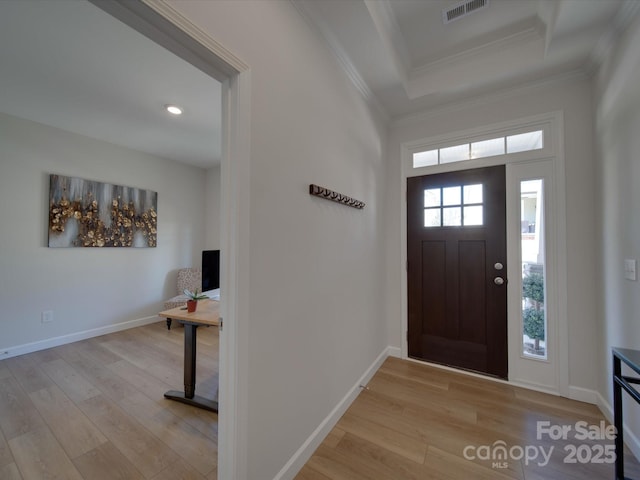 foyer entrance with a raised ceiling, light hardwood / wood-style floors, and crown molding