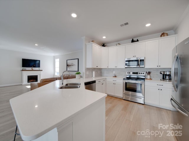 kitchen featuring white cabinetry, kitchen peninsula, stainless steel appliances, light hardwood / wood-style flooring, and sink