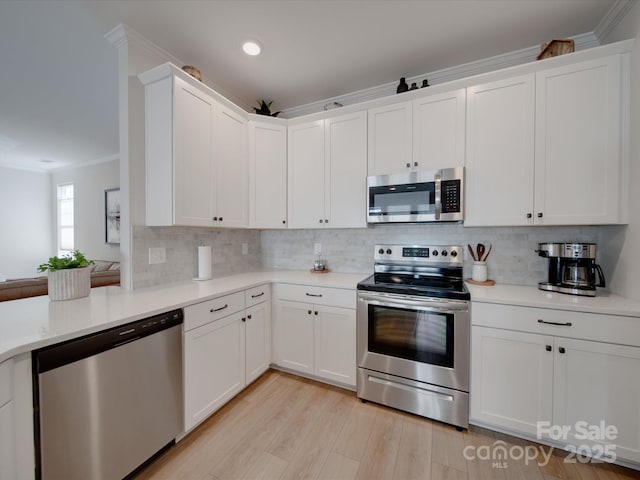 kitchen with white cabinets, appliances with stainless steel finishes, and crown molding