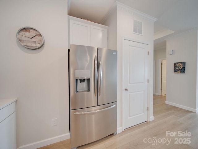 kitchen with white cabinetry, ornamental molding, stainless steel fridge with ice dispenser, and light hardwood / wood-style flooring