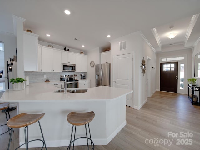 kitchen featuring white cabinetry, kitchen peninsula, stainless steel appliances, sink, and a breakfast bar area