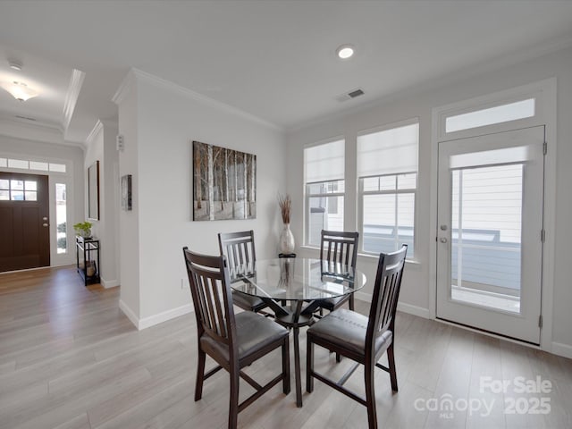 dining area with light hardwood / wood-style flooring and ornamental molding