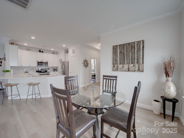 dining space featuring light hardwood / wood-style floors, sink, and ornamental molding